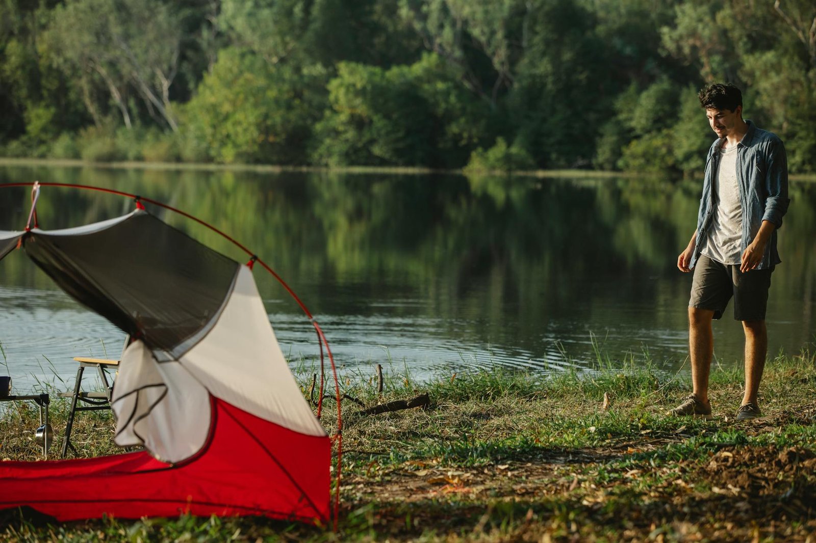 traveler on river shore against tent during summer journey