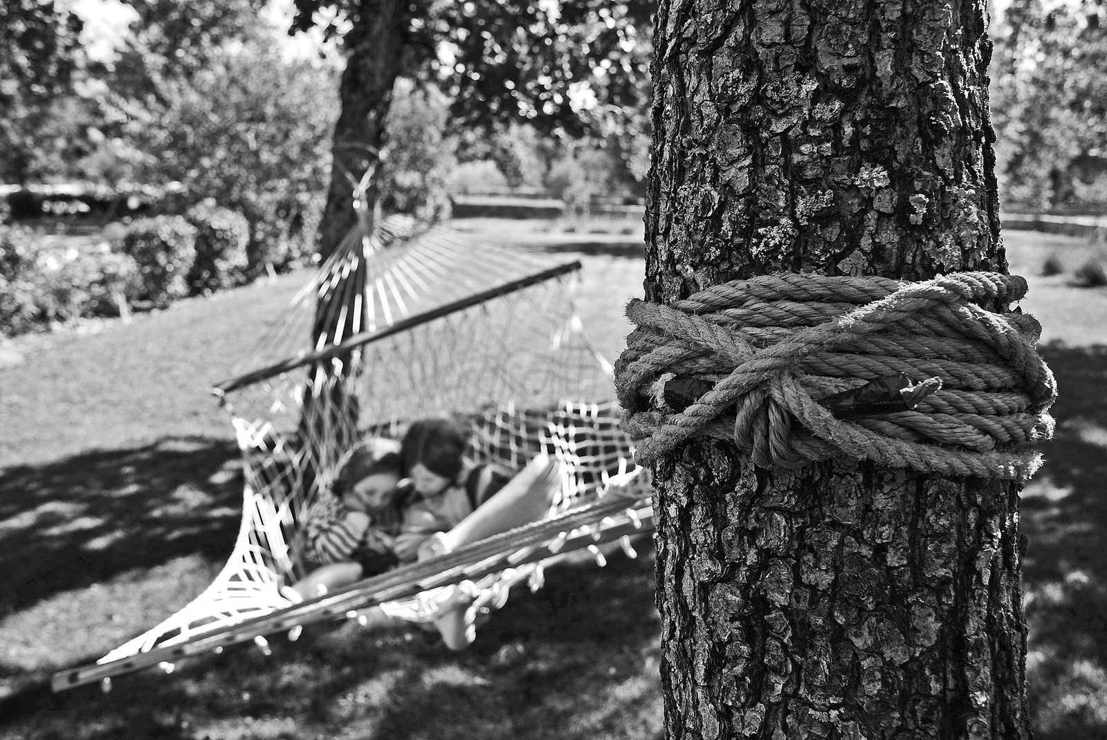 girl and boy on hammock grayscale photo