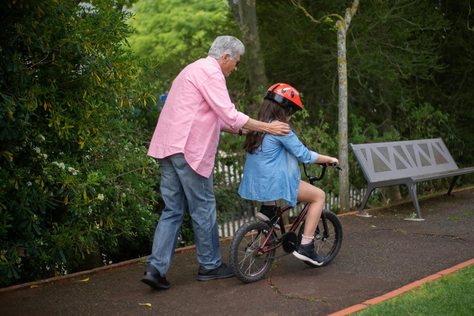 an elderly man teaching his grandchild to ride a bike